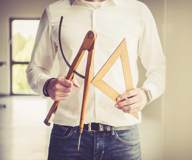 Foto eines Menschen welcher Zirkel und Geodreieck in den Händen hält.