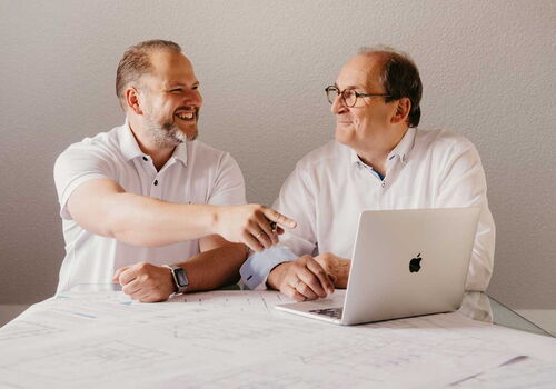 Die Geschäftsführer links Ingo Maaß und rechts Klaus Maaß sitzen vor einem Laptop und besprechen sich.